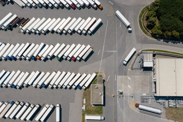 Vue aérienne zénithale d’une cour logistique avec des poids lourds rangés en épi, illustrant la réflexion sur le prix d’un TMS et le pilotage des coûts de transport.