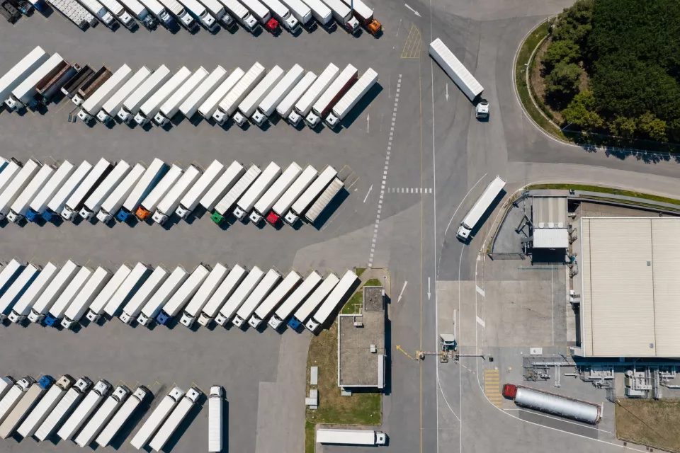 Vue aérienne zénithale d’une cour logistique avec des poids lourds rangés en épi, illustrant la réflexion sur le prix d’un TMS et le pilotage des coûts de transport.