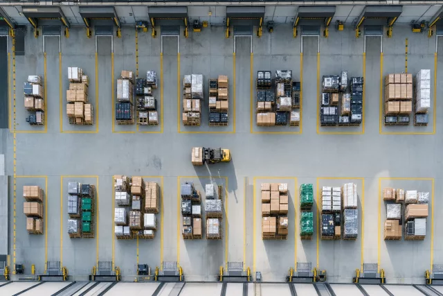Vue drone zénithale d’une zone de cross-dock avec des palettes de produits de seconde main et reconditionnés entre quais de réception et d’expédition, illustrant une logistique collaborative et tracée.