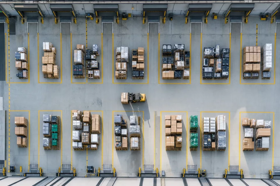 Vue drone zénithale d’une zone de cross-dock avec des palettes de produits de seconde main et reconditionnés entre quais de réception et d’expédition, illustrant une logistique collaborative et tracée.