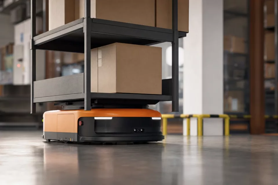 Photographie éditoriale en contre-plongée d’un robot mobile autonome transportant un rack sur le sol d’un entrepôt, illustrant la robotisation d’entrepôt et l’automatisation moderne.