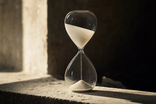 Sablier de laboratoire en verre posé sur une pierre calcaire, symbolisant l’échéance réglementaire et le traitement d’une facture PDF reçue par mail après septembre 2026.