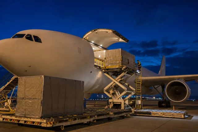 Avion-cargo chargé de conteneurs ULD sur un tarmac au crépuscule, illustrant les enjeux NIS 2 de la logistique, du transport et des échanges entre partenaires.